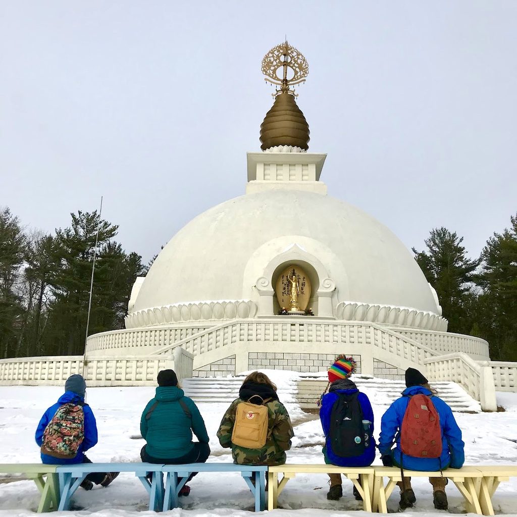people sitting in front of Peace Pagoda on an outdoor spiritual retreat