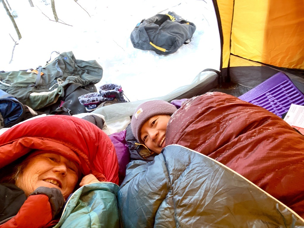 snuggled in sleeping bags for winter camping