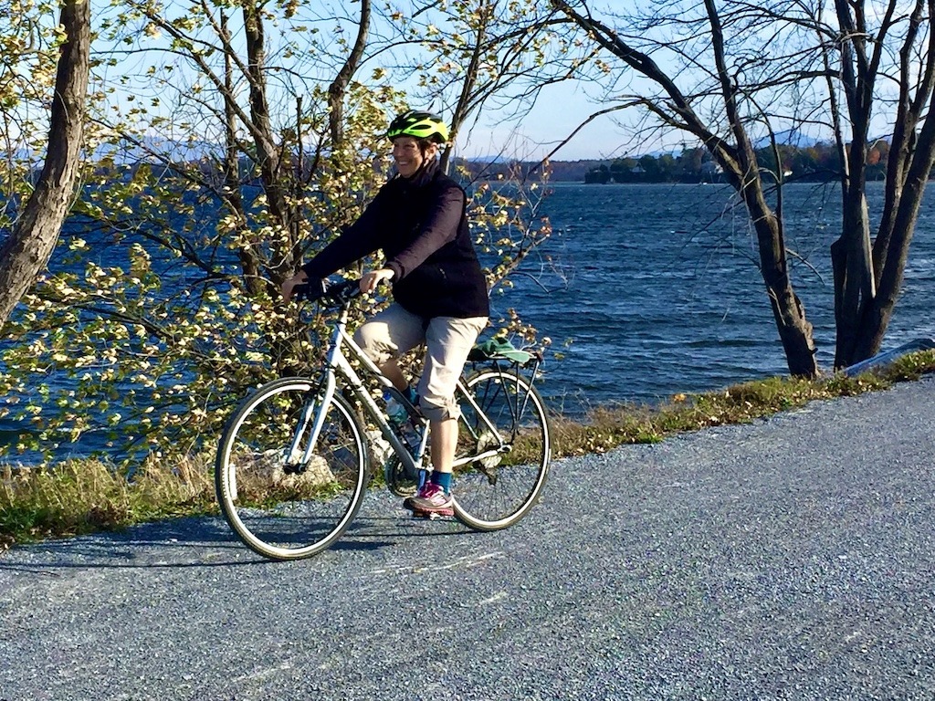 biker on bike trail beside water on the best bike trails in Vermont