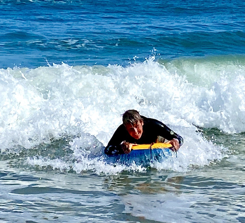 smiling woman on boogie board in surf- one of the outdoor adventures on Ocracoke Island