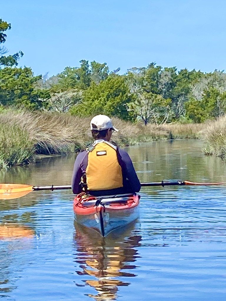 Kayaker in red kayak with yellow lifejacket -one of the outdoor adventures on Ocracoke Island