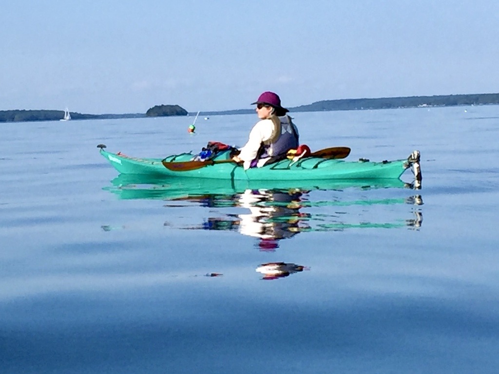 green boat on calm water-Maine sea kayak camping