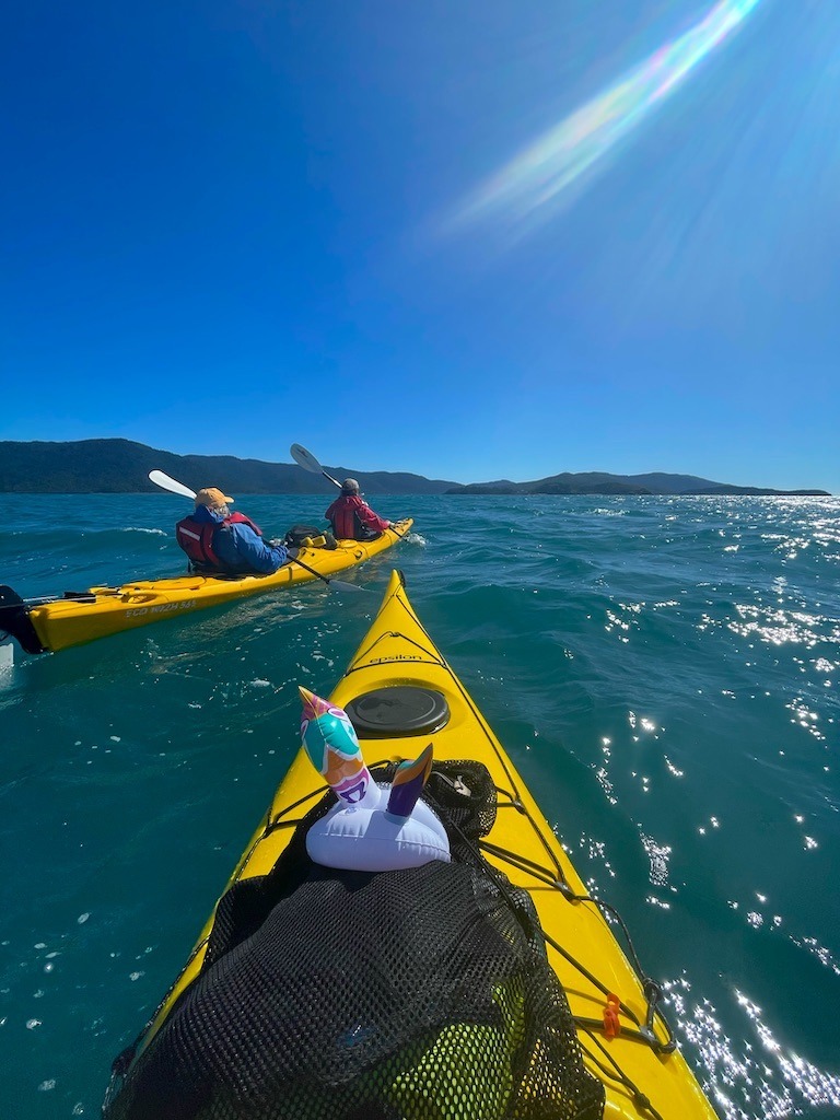 Sea kayaking in the Whitsunday Islands. 2 yellow boats with paddlers.