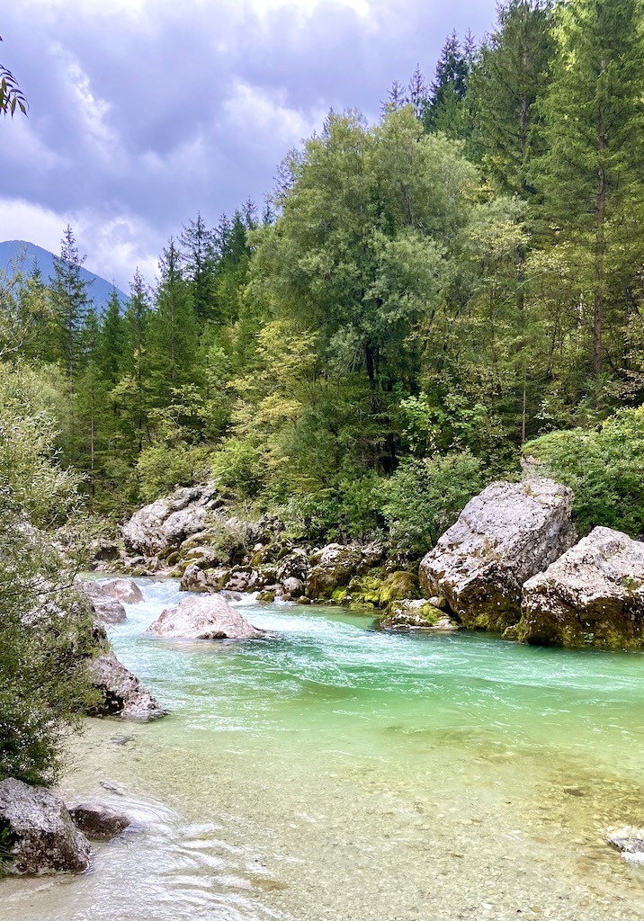 Emerald green water flowing by boulders