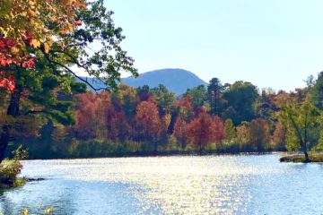 Pond with fall colors with blue mountain in background -the best hikes in the Holyoke Range