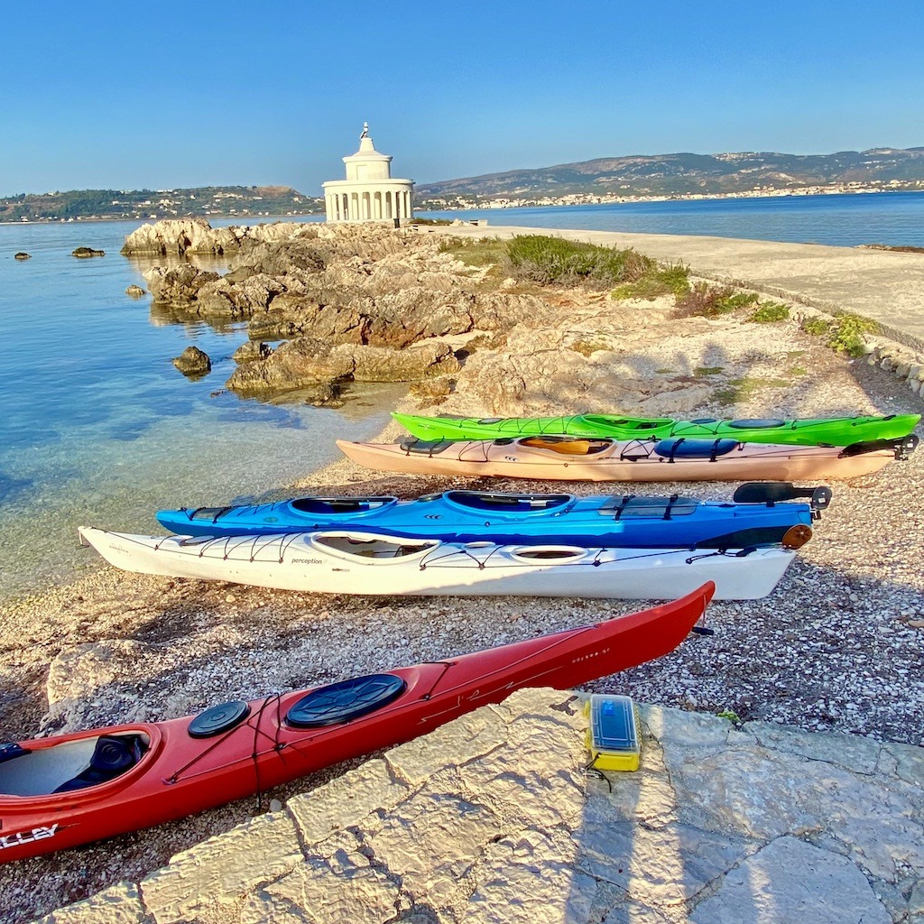 five sea kayaks on beach near white lighthouse-sea kayak on Kefalonia 