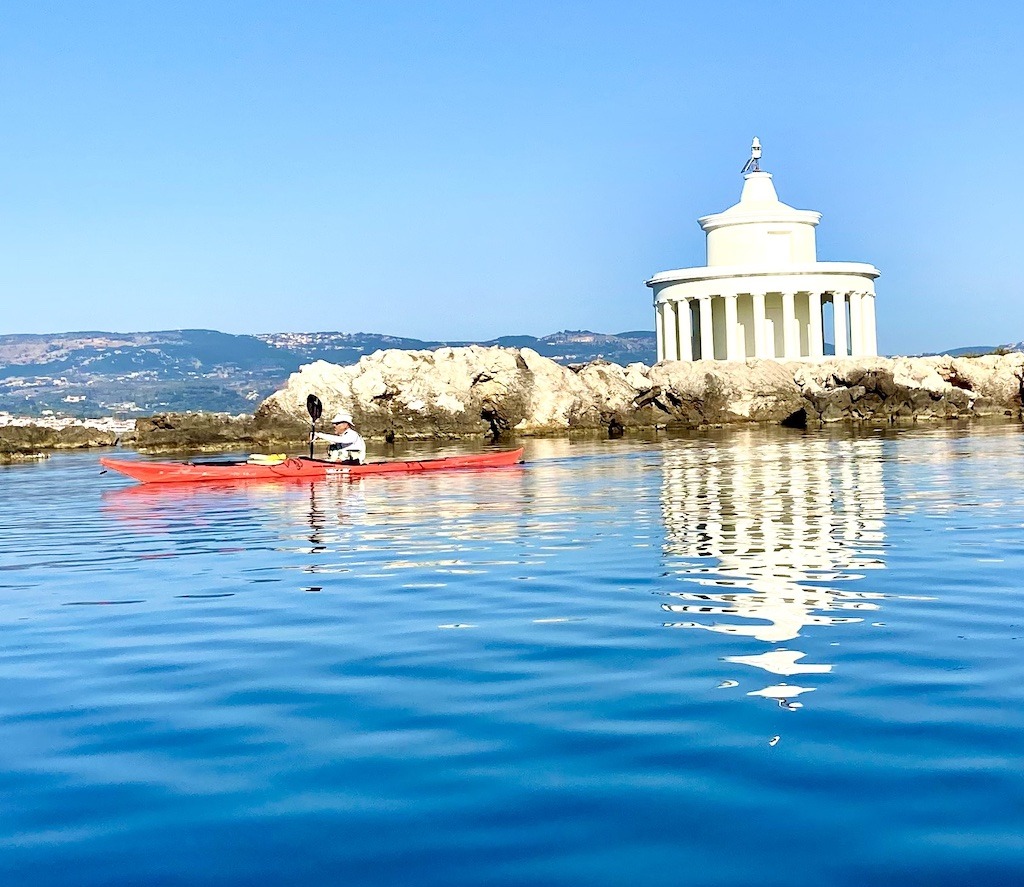 red boat paddler in front of white lighthouse-sea kayak on Kefalonia