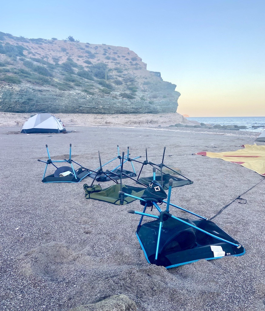camp chairs upside down on a beach with tent in the background.-Sea Kayaking in Baja