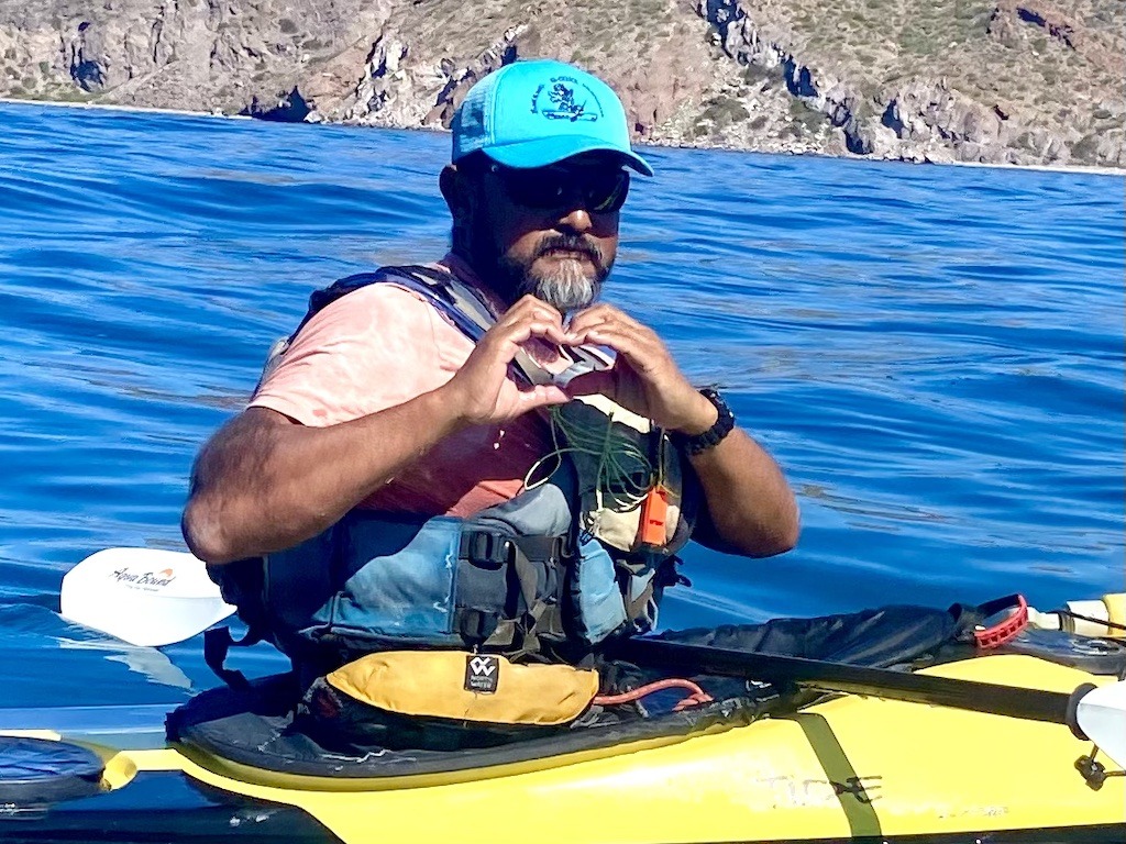man with beard and hat making heart sign. Sea Kayaking in Baja