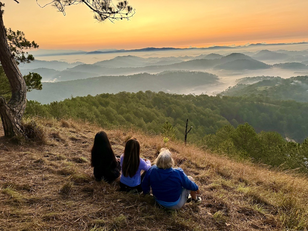 3 women overlooking clouds over mountains during outdoor adventures of Dalat