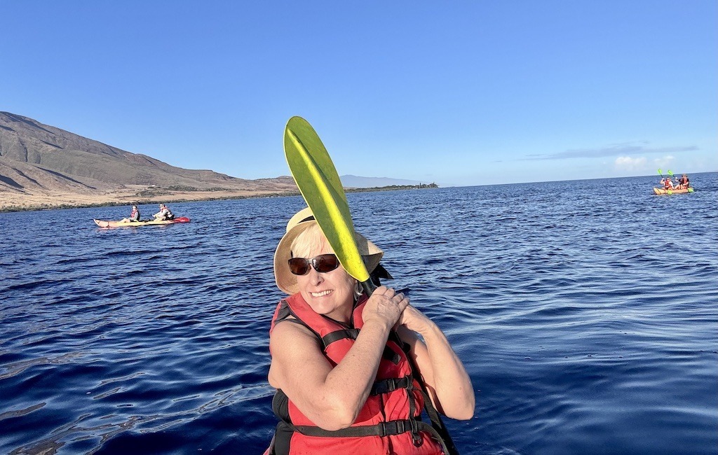 woman listening to whale songs through paddle while  Sea kayaking with whales in Maui