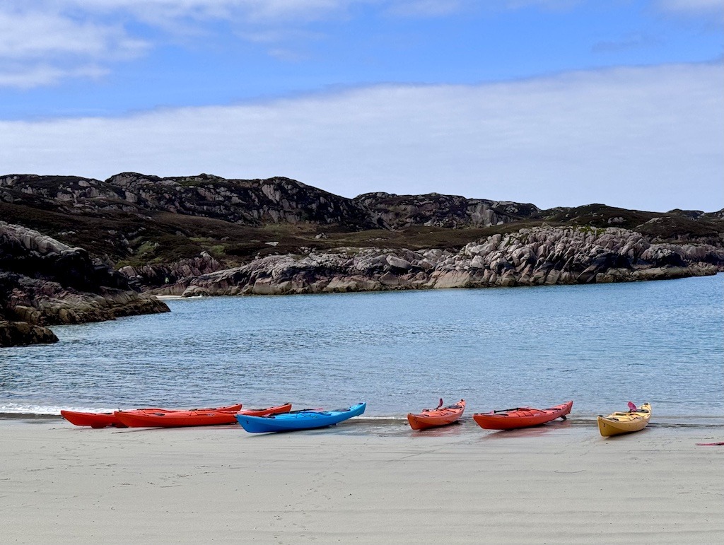 colorful kayaks on sand beach while sea kayaking in Scotland