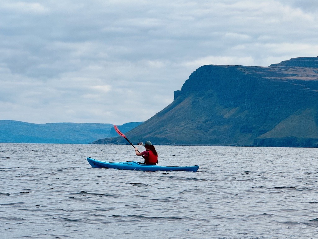 kayaker in blue boat sea kayaking in Scotland