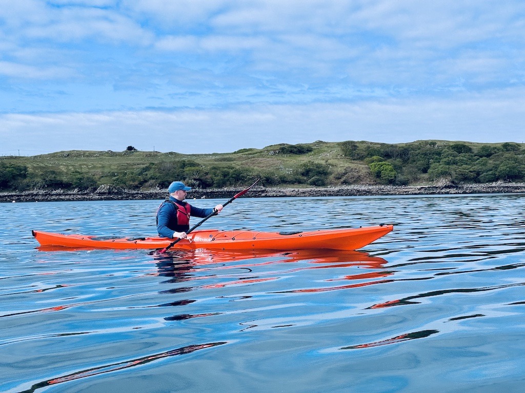paddler in red boat sea kayaking in Scotland