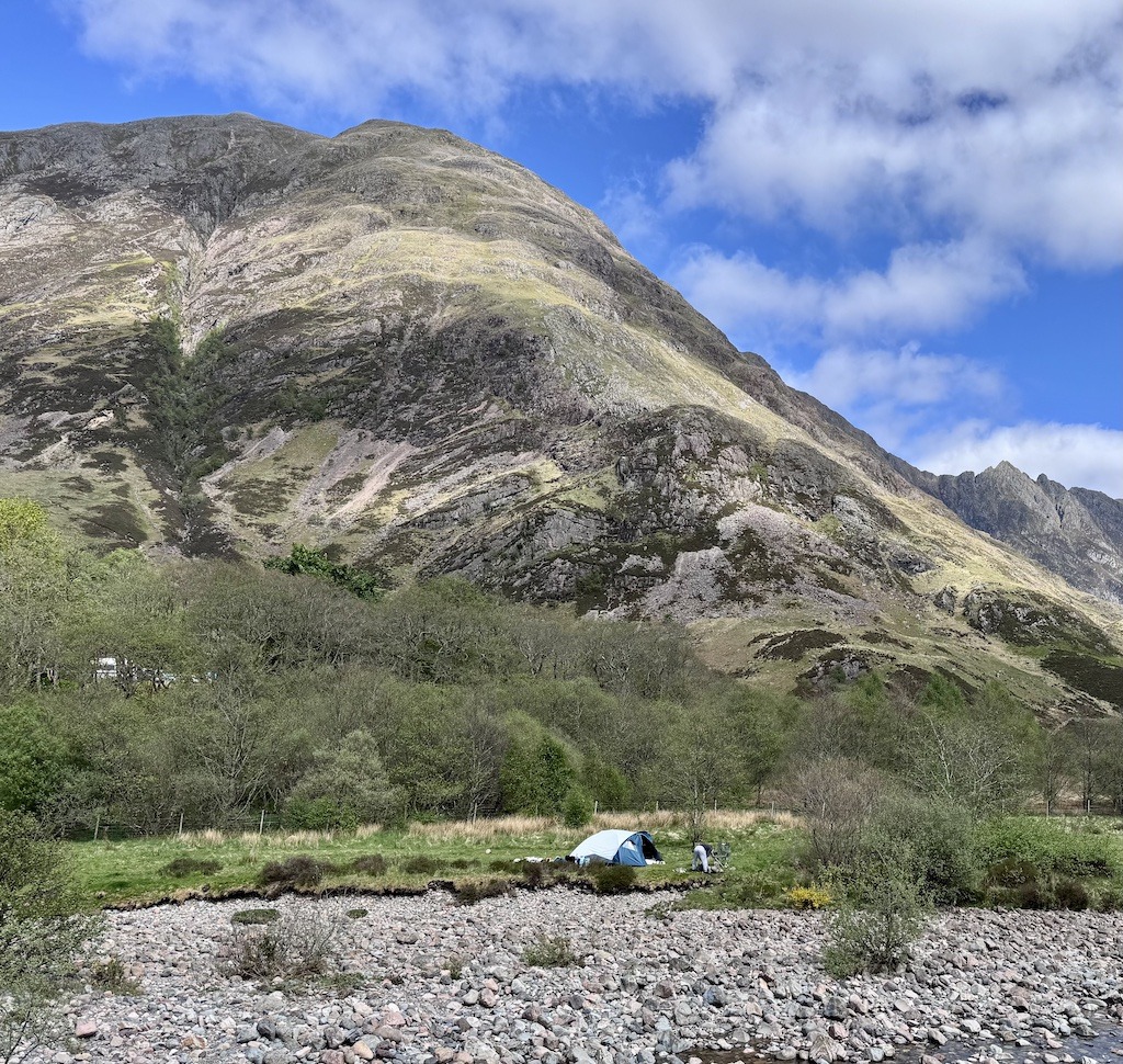 blue tent below a mountain-outdoor adventure trip planning in Scotland
