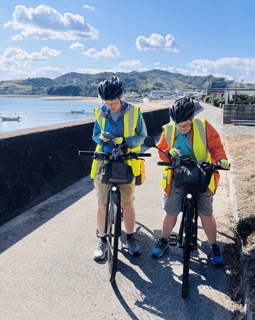 2 bikers looking at phones while biking the Shimanami Kaido