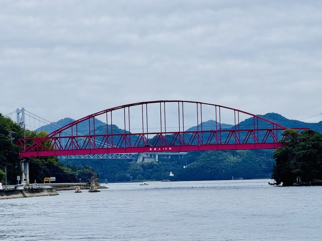 Red bridge in front of white bridge seen while biking the Shimanami Kaido