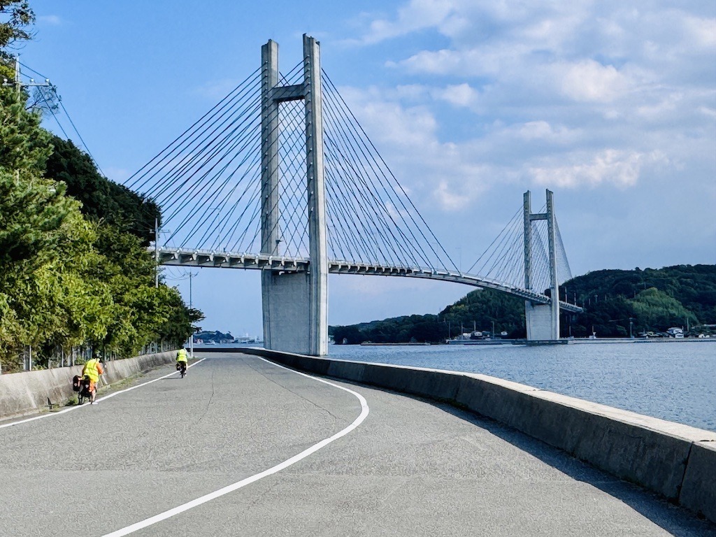 2 bikers approaching a bridge while biking the Shimanami Kaido