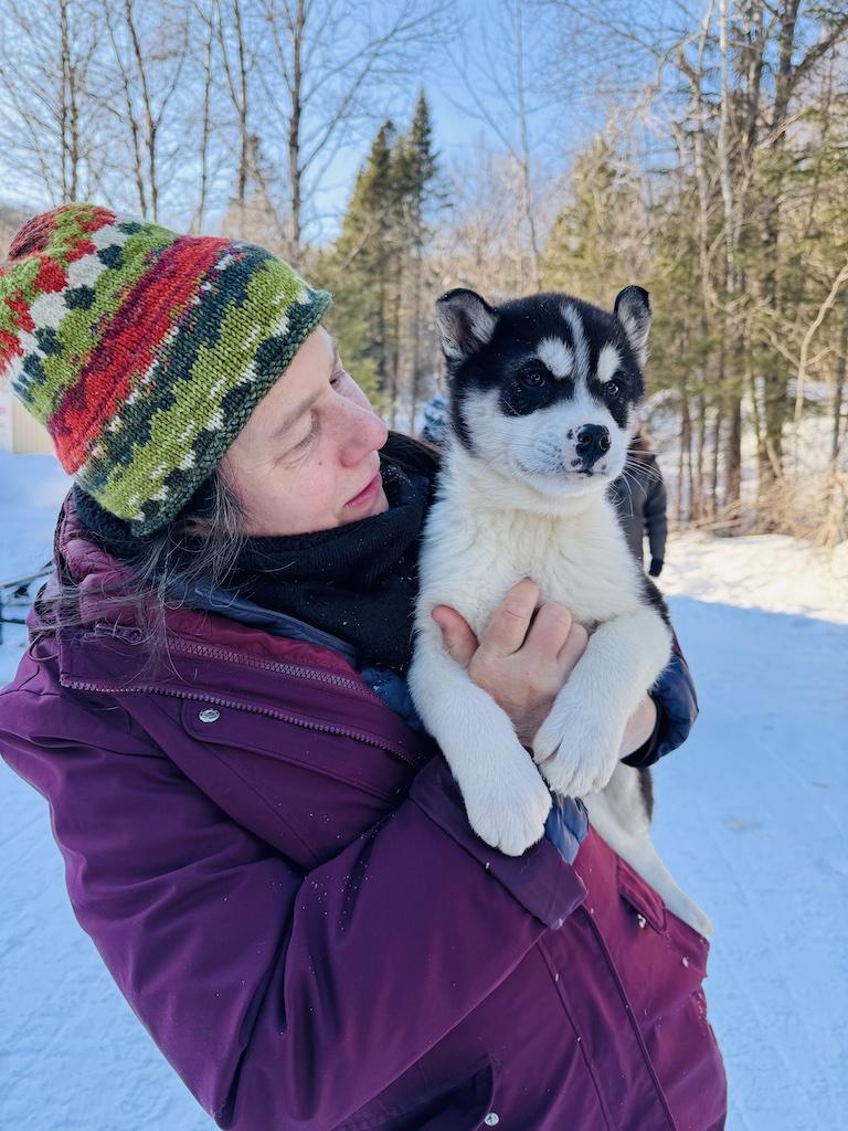 person in red holding a puppy while Dogsledding in Quebec