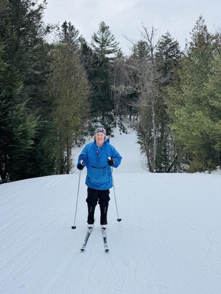 woman with blue windbreaker cross country skiing at Craftsbury