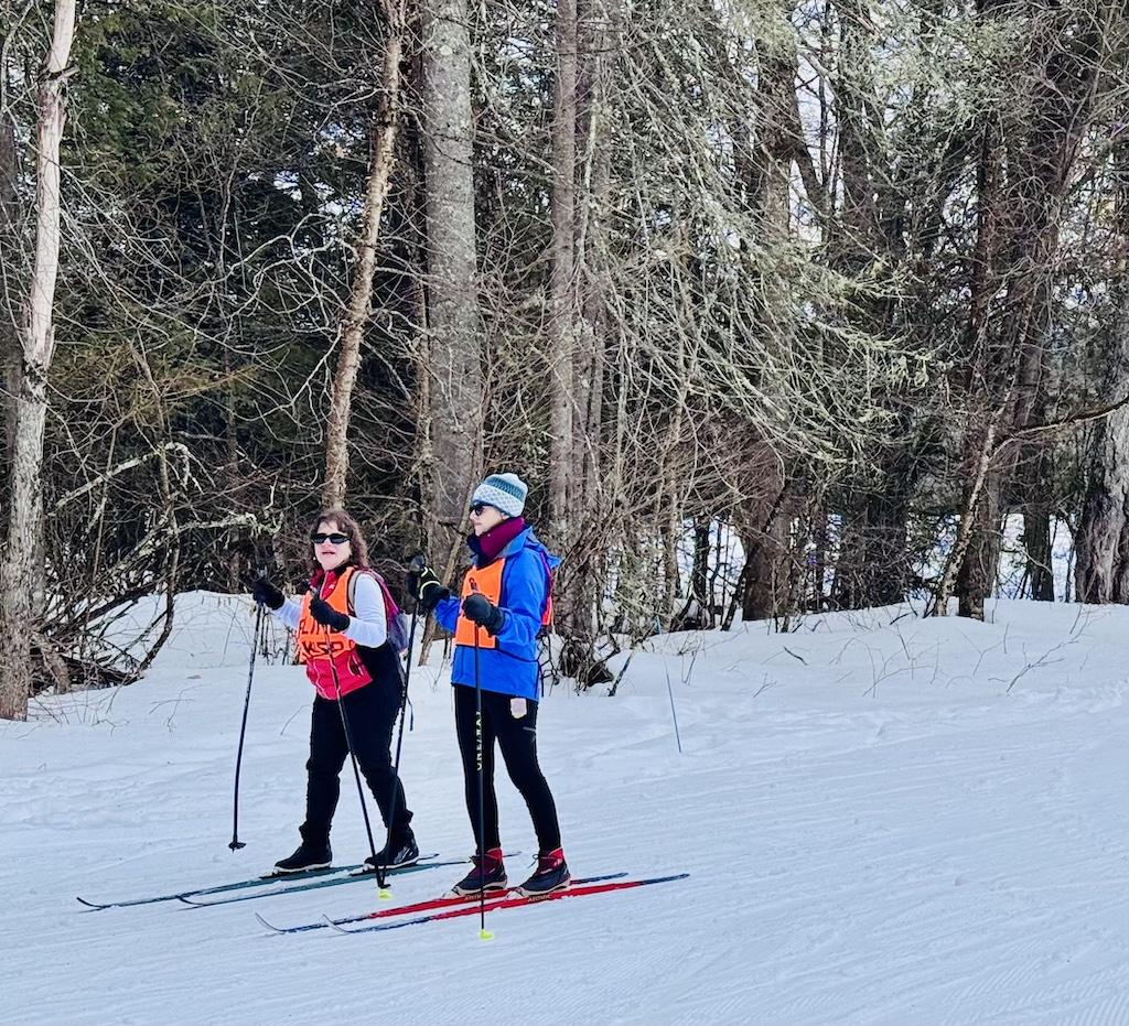 skiers with orange vests cross country skiing at Craftsbury