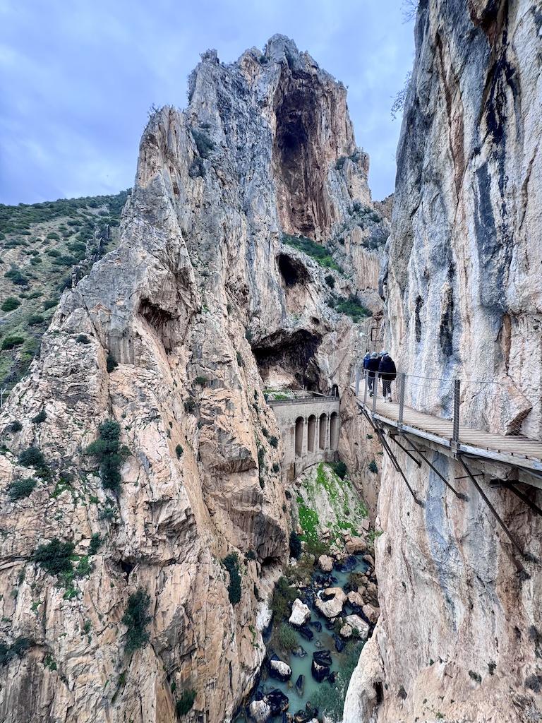 limestone cliff towering over walkway with hikers on the Caminito del Rey hike