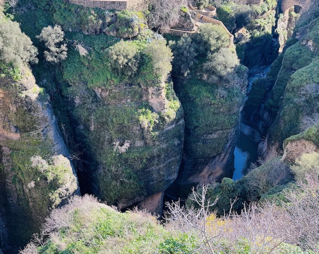 Cliff with green and river below seen while doing outdoor adventures in Andalusia