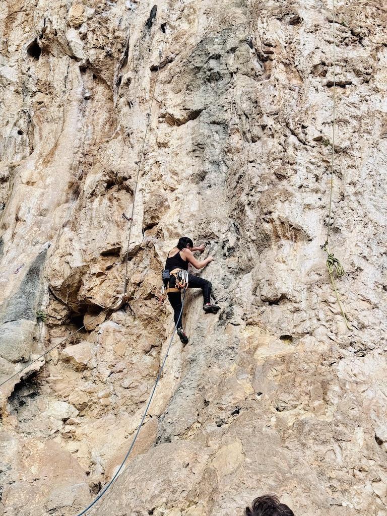 woman in black rock climbing on brown cliff while doing outdoor adventures in Andalusia