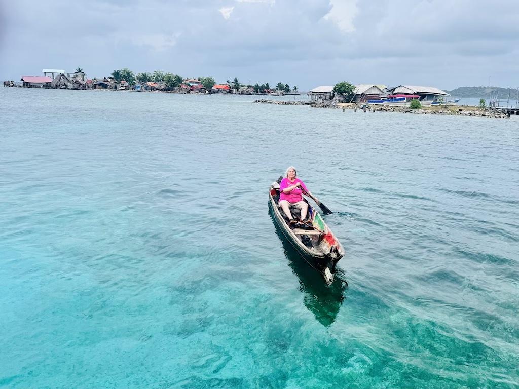 women in pink paddling a dugout canoe on a Cultural Tour of the San Blas Islands