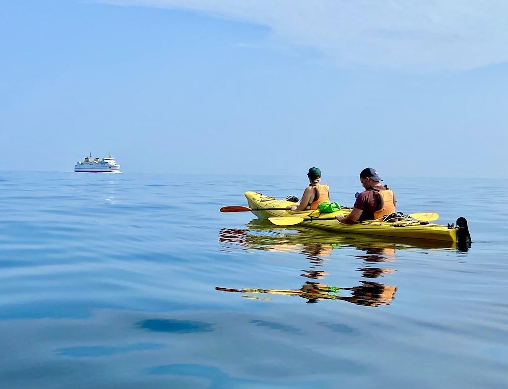 kayakers in yellow boat watching a ferry on an International sea kayaking trip
