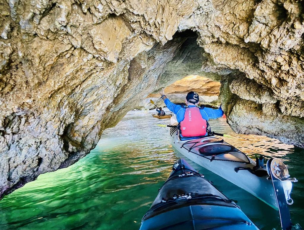 man with black hat kayaking in cave on an International sea kayaking trip