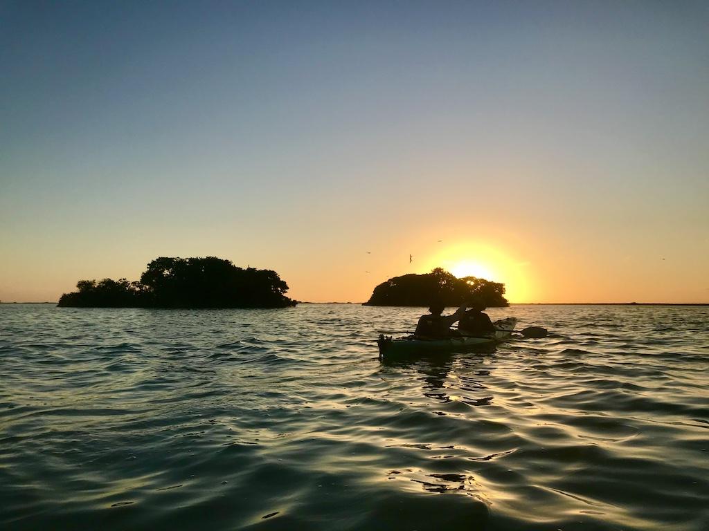 sunset paddlers with island on International sea kayaking trip