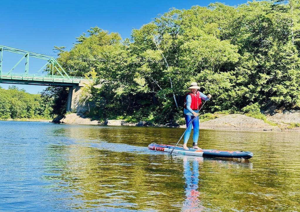 woman paddling on paddleboard with bridge behind her-outdoor adventures in Bethel