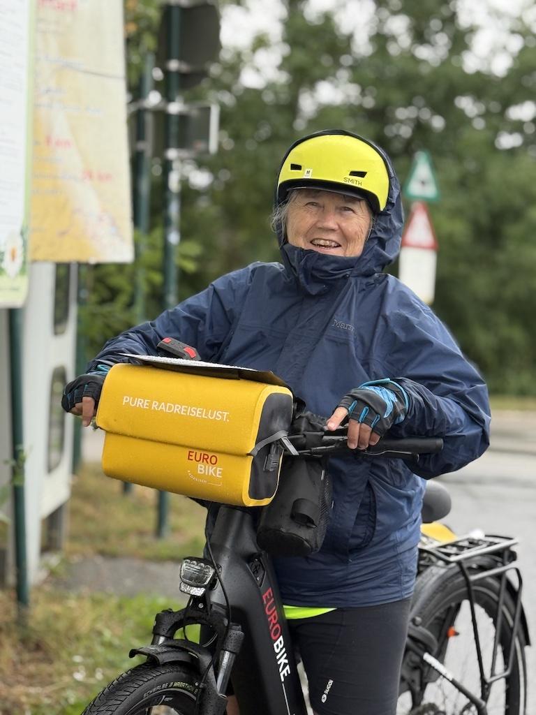 women in blue on bike with yellow bags--while biking along the Danube River
